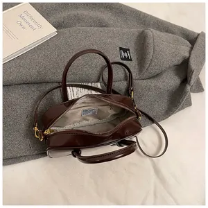 Detail view of the deep brown glossy leather handbag with zipper and fabric lining