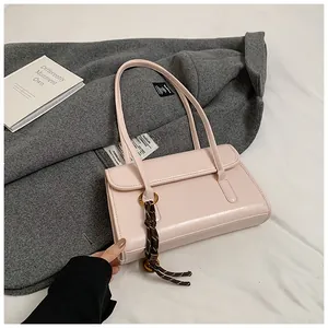Close-up of light pink leather shoulder bag with fine straps and woven knot charm detail