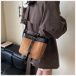 Detail of color-block crossbody bag with studs and leather strap on model