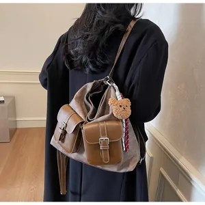 Detail of grey-brown tote bag with plush bear charm and vintage brown pocket buckles