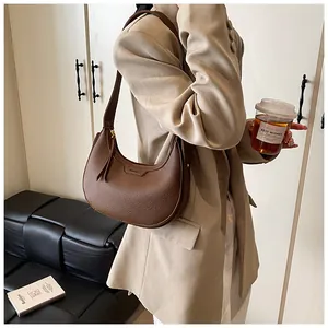 Dettaglio della borsa hobo in pelle martellata marrone con logo e tracolla larga