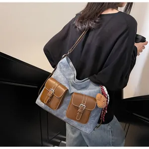Blue denim and brown leather tote bag detail with buckled pockets and bear charm charm
