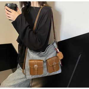 Detail of grey canvas tote bag with brown pockets and cute bear charm shown on model