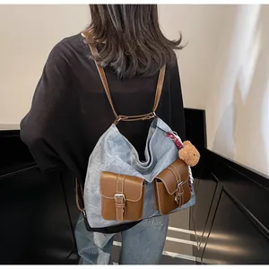 Detail of denim tote bag with brown leather pockets and a small plush bear pendant