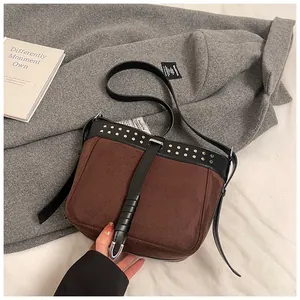 Detail of retro suede messenger bag with silver rivets and black leather trim accents