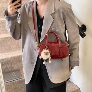 Deep red glossy leather square handbag worn with a grey oversized blazer and plush charm