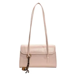 Minimalist light pink rectangular underarm bag with thin straps and woven bell charm