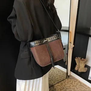Vintage brown suede bucket bag with black leather trim and silver rivets on shoulder