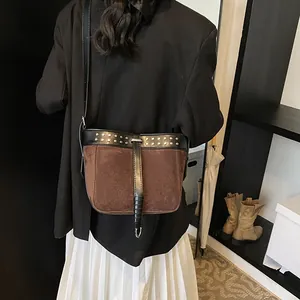 Vintage brown suede bucket bag with black leather trim and metal rivets on model