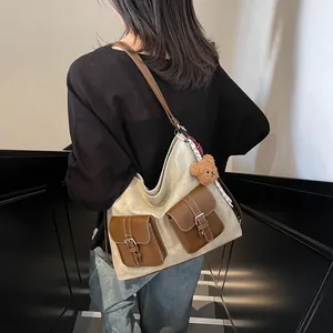Chic cream canvas tote bag with brown leather pockets shown on model in a modern interior
