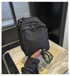 Detail of black nylon shell bag with dual metal zippers and woven shoulder strap
