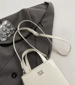 Detail of adjustable shoulder strap and silver hardware on white minimalist crossbody bag