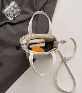 Spacious interior of white faux leather tote bag showing items like power bank and spray