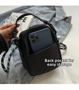 Macro detail of the back patch pocket on a black nylon mini crossbody bag with a phone