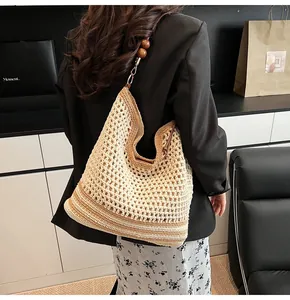 Detail of hollow-out straw hobo bag with striped bottom and decorative dark wooden beads