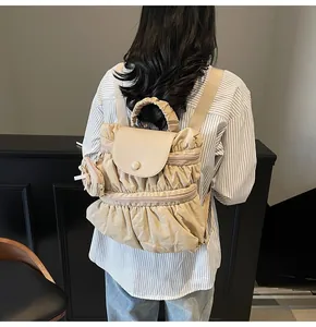 Gedetailleerd zicht op beige geplooide rugzak met bijpassend mini-tasje op model