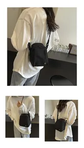 Detail of minimalist black canvas crossbody bag with dual zippers and woven strap