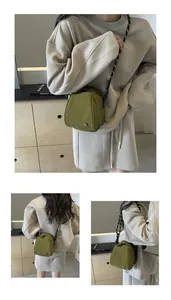 Detail of olive green nylon crossbody bag with black and white woven shoulder strap
