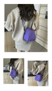 Detail of purple mini crossbody bag featuring a patterned strap and secure zipper closure