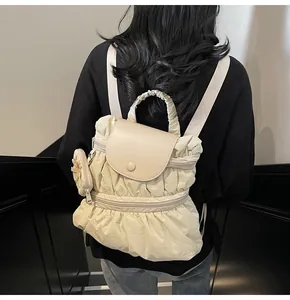 Detailweergave van crème plissé rugzak met bijpassende ronde munttas op een model