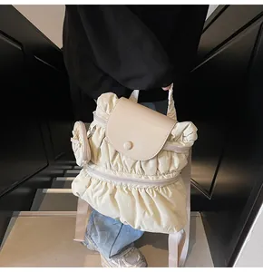 Detailopname van crèmekleurige rugzak met geplooide stof, ruches en kleine ronde portemonnee