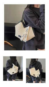Close-up of cream straw tote bag with black piping and branding detail on straps