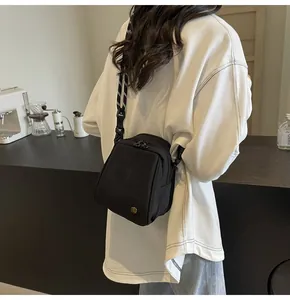 Detailed view of mini black canvas crossbody bag with decorative woven rope strap
