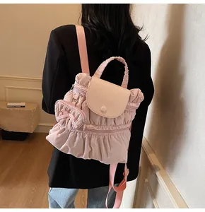 Detail van een roze geplooide rugzak met een bijpassende hartvormige hanger en lederen flap