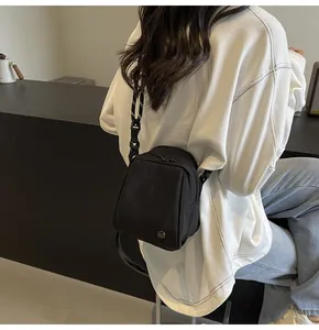 Rear view of black nylon crossbody shell bag with black and white woven rope shoulder strap