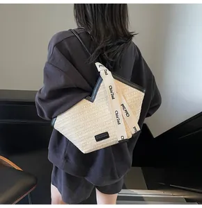 Detailed view of cream straw tote bag with black trim and brand ribbon on model
