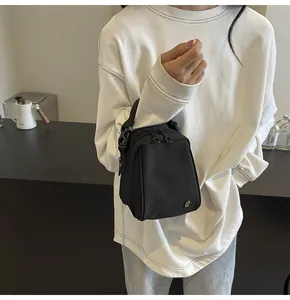 Detail of black shell crossbody bag with dual zippers and silver decorative buckle
