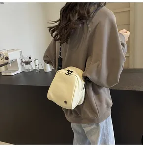 Close-up of creamy white PU leather crossbody bag with black zipper and adjustable strap