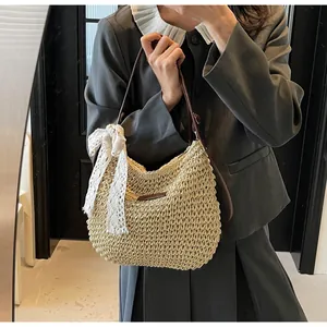 Close-up of woven straw bucket bag featuring a white lace bow and brown leather strap