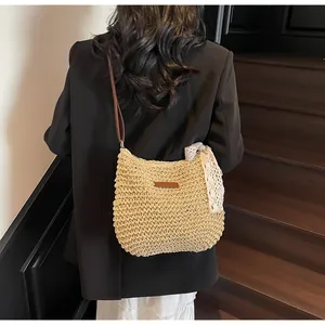 Detail of hand-woven straw crossbody bag with white lace bow and leather strap