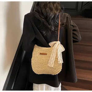 Detail of hand-woven straw crossbody bag with white lace bow and brown leather strap