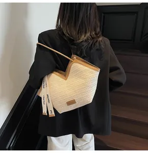 Detail of cream woven tote bag featuring brown leather trim and stylish V-shape opening