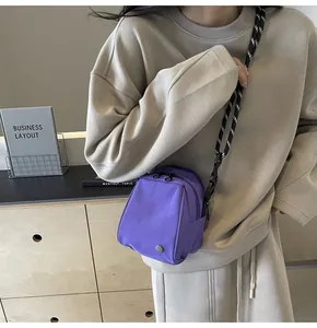 Detail of purple nylon shell bag featuring dual zippers and adjustable patterned strap