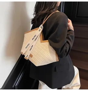 Detail of the woven tote bag with brown leather trim and lettered strap on model