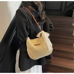 Detail showing the white lace bow and brown leather strap on the woven straw bucket bag