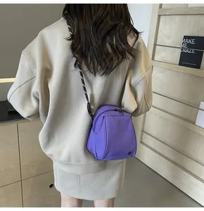 Purple nylon shell crossbody bag with adjustable striped strap and metal logo detail