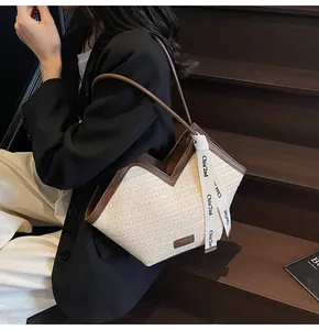 Detail of woven tote bag featuring a V-shaped cut, brown leather trim and decorative ribbon