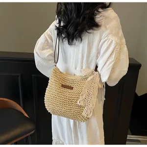Model back view showing woven straw crossbody bag with white lace bow and brown strap