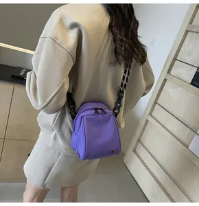 Detail of purple nylon shell crossbody bag with adjustable striped woven shoulder strap
