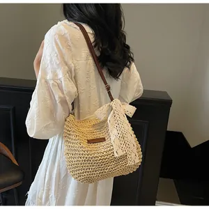 Detail of woven straw crossbody bag featuring a large cream lace bow and leather strap
