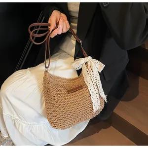 Detail of hand-woven straw hobo bag with brown strap and white lace bow decoration