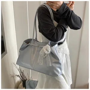 Close-up of light blue soft leather tote bag with lace bow and pearl charm detail