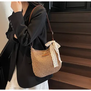 Detail of hand-woven straw shoulder bag with white lace bow and brown leather strap