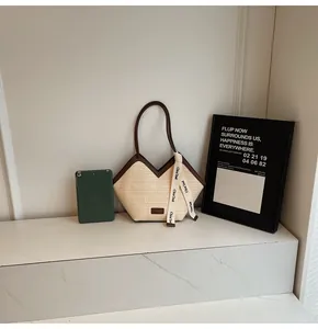 Detail of minimalist beige woven tote bag with brown leather handles and decorative ribbon