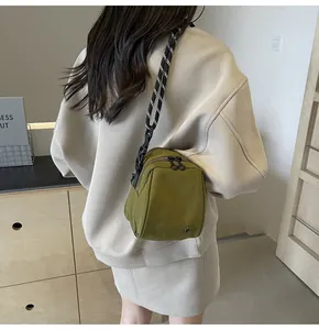 Olive green nylon shell bag featuring dual zipper closure and braided shoulder strap