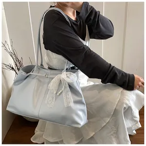 Detail of light blue faux leather tote bag with white lace bow and pearl pendant charm